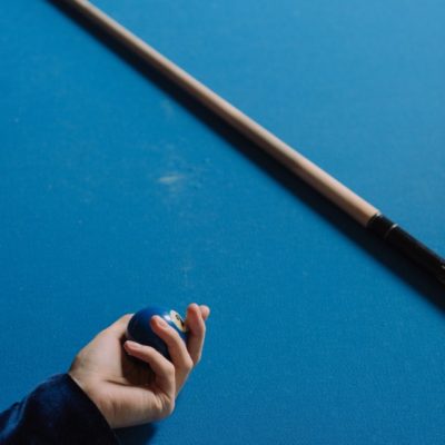 person holding one blue ball, one pool stick
