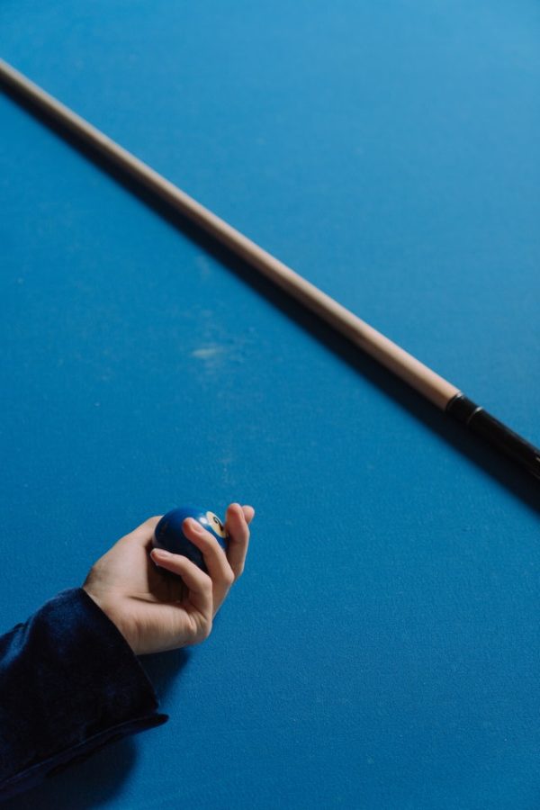 person holding one blue ball, one pool stick
