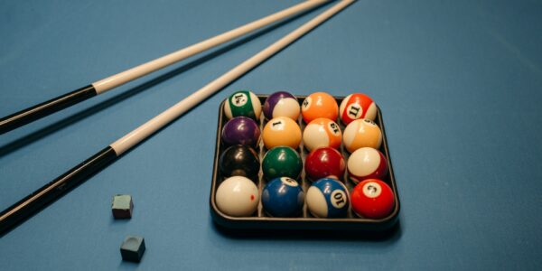 cue chalks, pool sticks and balls in a triangle